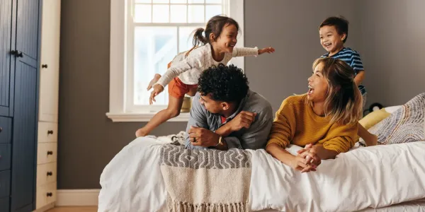 family laughing and jumping on bed
